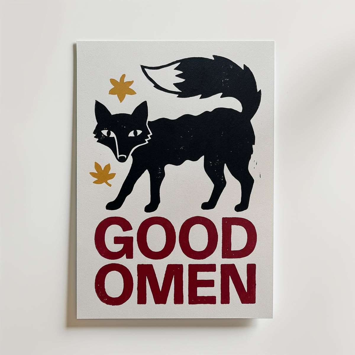Good Omen Fox – affisch med naivistisk svart räv med senapsgula blad i svart ram, tryckt i Sverige hos Bozetto